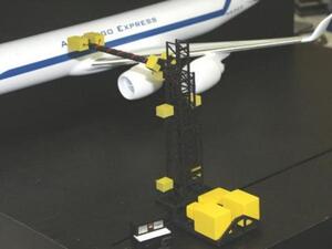 Aircraft inspection model with a black lattice tower and boom arm reaching a white airliner's fuselage above its engine