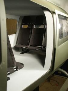 LUH helicopter model cabin seen through the open side door, showing fabric troop seats and a riveted window