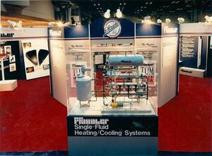 Heating and cooling system scale model with tanks, piping and pump in an acrylic case on a trade show booth pedestal