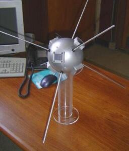 Full scale Vanguard satellite model on a clear acrylic stand atop an office desk, with antenna rods extended