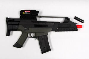 Airsoft rifle replica in black and olive drab, side view with laser sight and detached flash hider at the muzzle