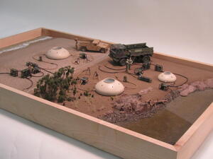 Water purification system diorama in a maple wood frame, with dome tanks, pumps, trucks and a rocky riverbank