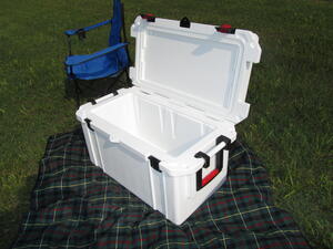 Full-size cooler model with lid open, showing white interior and ribbed walls, set on a plaid blanket outdoors