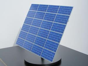 Solar panel model tilted on a round black base, blue cell grid of the 24-module array facing the viewer