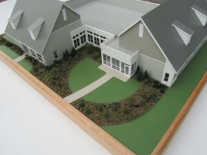 Retirement community model with gray gabled roofs and dormers, curved lawns and landscaped courtyard on an oak-framed base