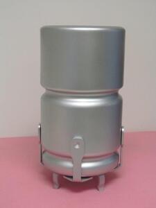 Oversized capacitor model with a silver cylindrical body, grooved bands and bracket legs, standing upright on a pink surface