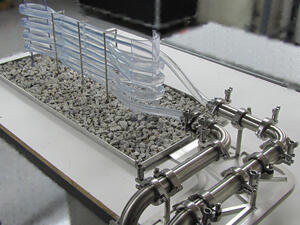 Working bioreactor model with clear algae tubes layered over a gravel bed and stainless steel piping with sanitary clamps