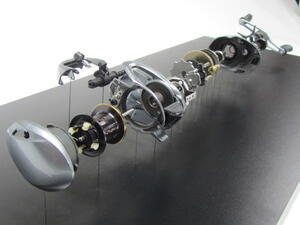 Exploded baitcasting reel display model, parts suspended on thin wires above a black base, viewed from the spool end