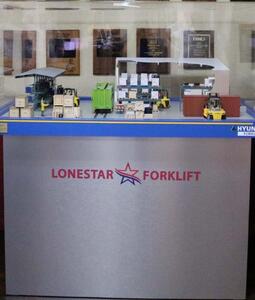 Forklift diorama in a glass-covered case on a silver base, with lumber rack, rail car, warehouse shelving and container