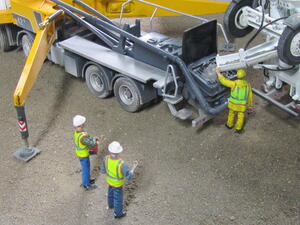 Concrete pump truck hopper receiving mix from a cement mixer chute as workers watch, high angle view of the diorama