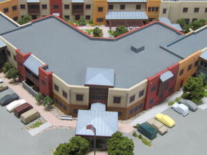 Retirement home architectural model, aerial view of the covered main entrance, flagpole, curved facade and parked cars