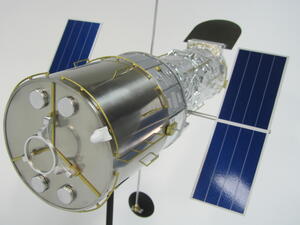 Hubble telescope model aft end with brushed aluminum bulkhead, round caps and brass handrails, solar arrays behind