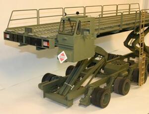 60K Tunner cargo loader model at a front three-quarter angle, deck raised on scissor lifts above the chassis