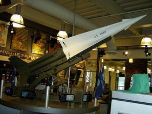 Nike Hercules missile model on its angled launcher, white missile marked U.S. Army, on a round museum display base