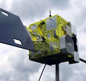 GOES-12 satellite model on a pole, seen from below with gold foil body, solar array arm and sensor housings
