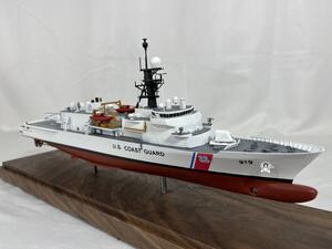 Coast Guard cutter model with hull number 919 on a walnut base, bow three-quarter view showing mast and small boats