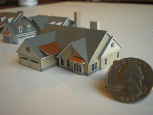 Tiny house architectural model with gray roofs, dormers and garage doors, shown beside a US quarter for scale