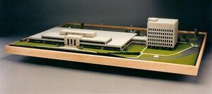 Office building architectural model with low-rise wing, multistory tower, lawns and rear parking on a wood-framed base