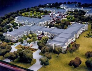 Retirement community architectural model from above, showing connected residential wings, tree-lined lawns and a parking lot