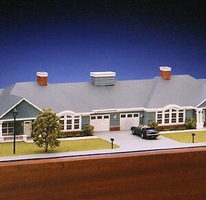 Retirement cottage model front close-up with twin garage doors, brick chimneys, arched windows and a parked car