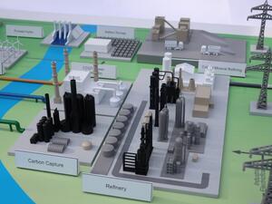 Energy site scale model close-up of labeled carbon capture and refinery areas, with CCGT plant and pylons behind