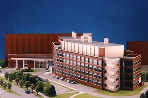 Research center architectural model with multistory brick lab building, rooftop exhaust stacks, parking lot and trees