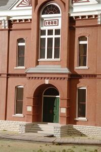 Court house model entrance close-up with arched doorway, green double doors, stone steps and 1888 date plaque