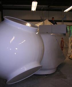 Wind turbine nacelle and hub model seen from the front, glossy white hub with open blade ports under shop lights