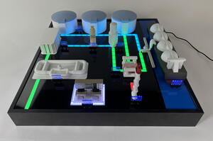 LNG regasification plant model with green and blue LED flow lines lit across a black base, tanks and LNG carrier ship