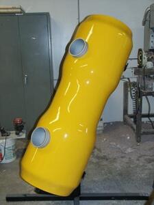 Full-size TITAN energy recovery device model in glossy yellow, tilted on a black steel stand showing two round ports
