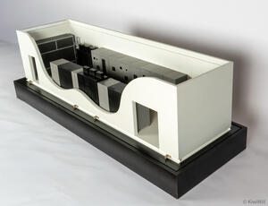 MCPU power container scale model with curved cutaway wall revealing cabinet rows, on a black display base