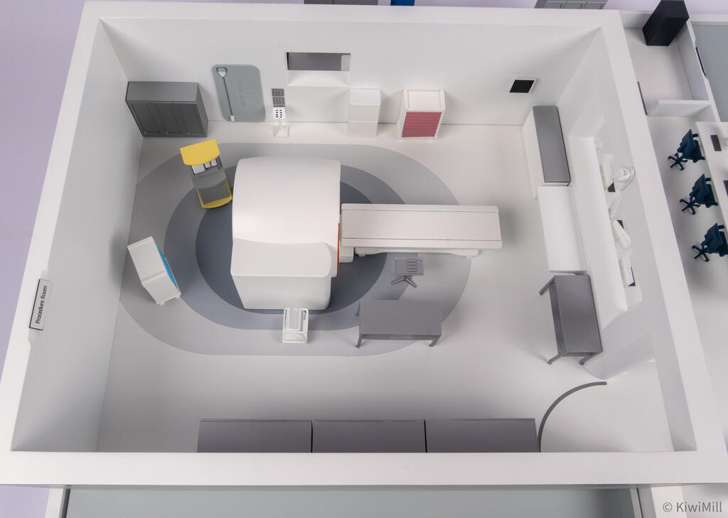 Top-down view of the procedure room with the scanner centered on circular gray floor markings and wall cabinets
