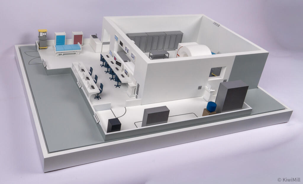 Three-quarter view of the complete suite on its white base, procedure room walls rising beside the open lower rooms