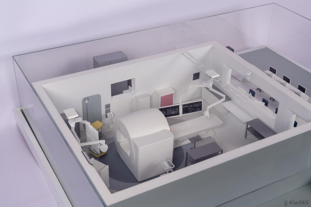 Angled view of the procedure room under the clear acrylic cover, showing the boom monitors and overhead rails