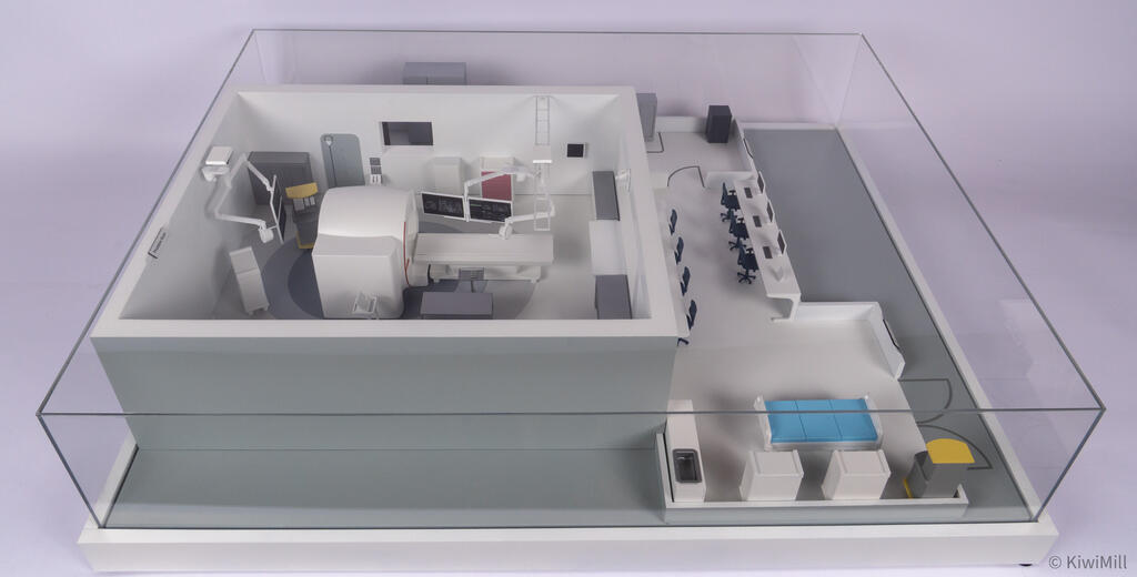 Complete MRI suite model under its clear acrylic display cover, viewed from the front with boom monitors installed