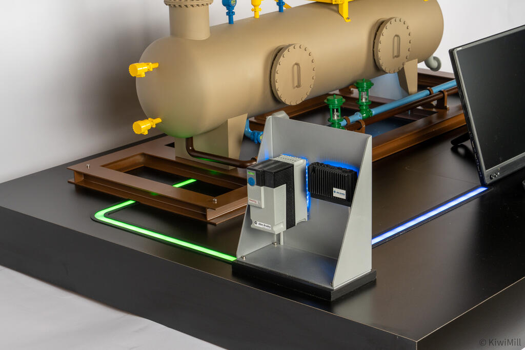 Automation devices on the angled gray stand with blue backglow, green light path curving toward the skid frame