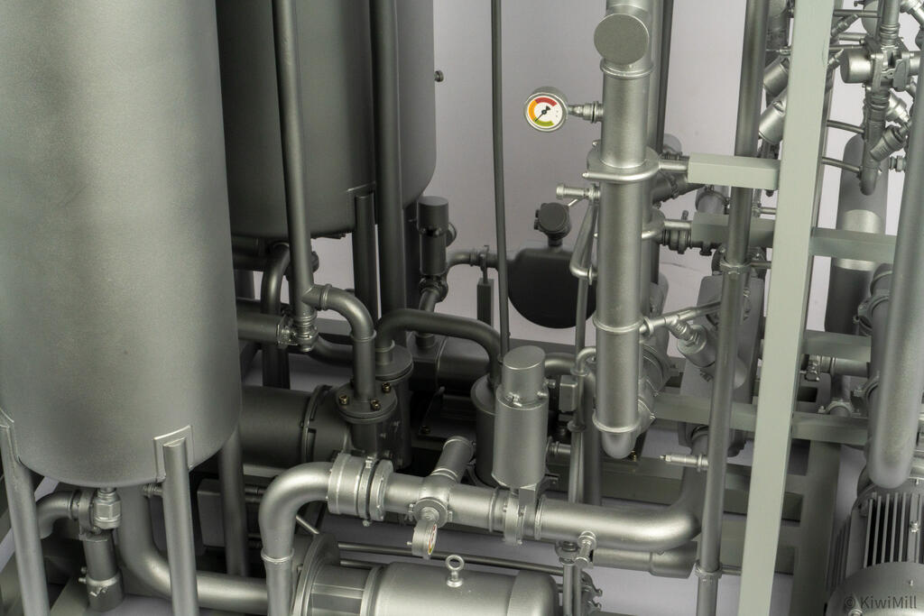 Close-up of piping between the tanks with a colored pressure gauge, sanitary clamp fittings and pump below