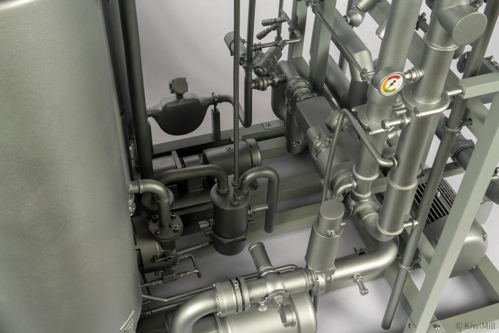 Overhead close-up into the skid showing mass flow meter, pump housing, gauge and clamped pipe bends