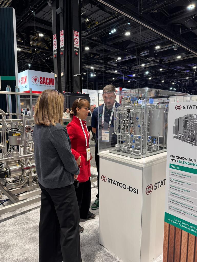 Visitors examining the blending system model under its acrylic cover at the Statco-DSI trade show booth